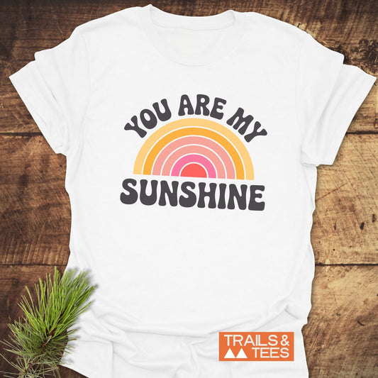 You Are My Sunshine T-Shirt featuring a rainbow and pine branch design on the front. Perfect for casual, uplifting style.