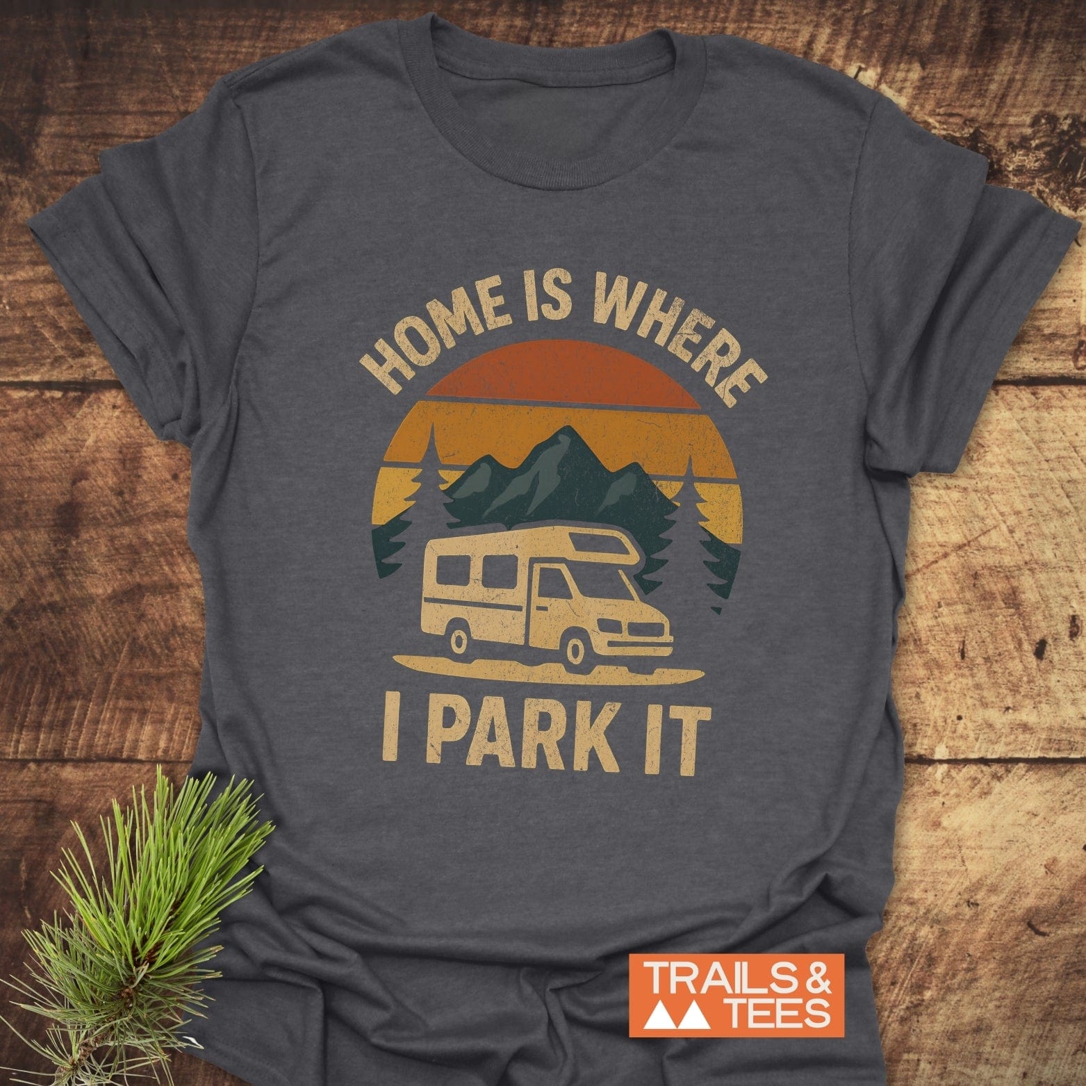 Home Is Where I Park It T-Shirt featuring a camper van, mountains, and pine branch design, crafted from soft cotton for daily outdoor adventures.