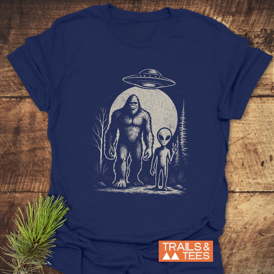 Bigfoot And Alien T-Shirt featuring an alien and UFO graphic. Made from soft, lightweight cotton. Pre-shrunk with durable prints, no side seams.