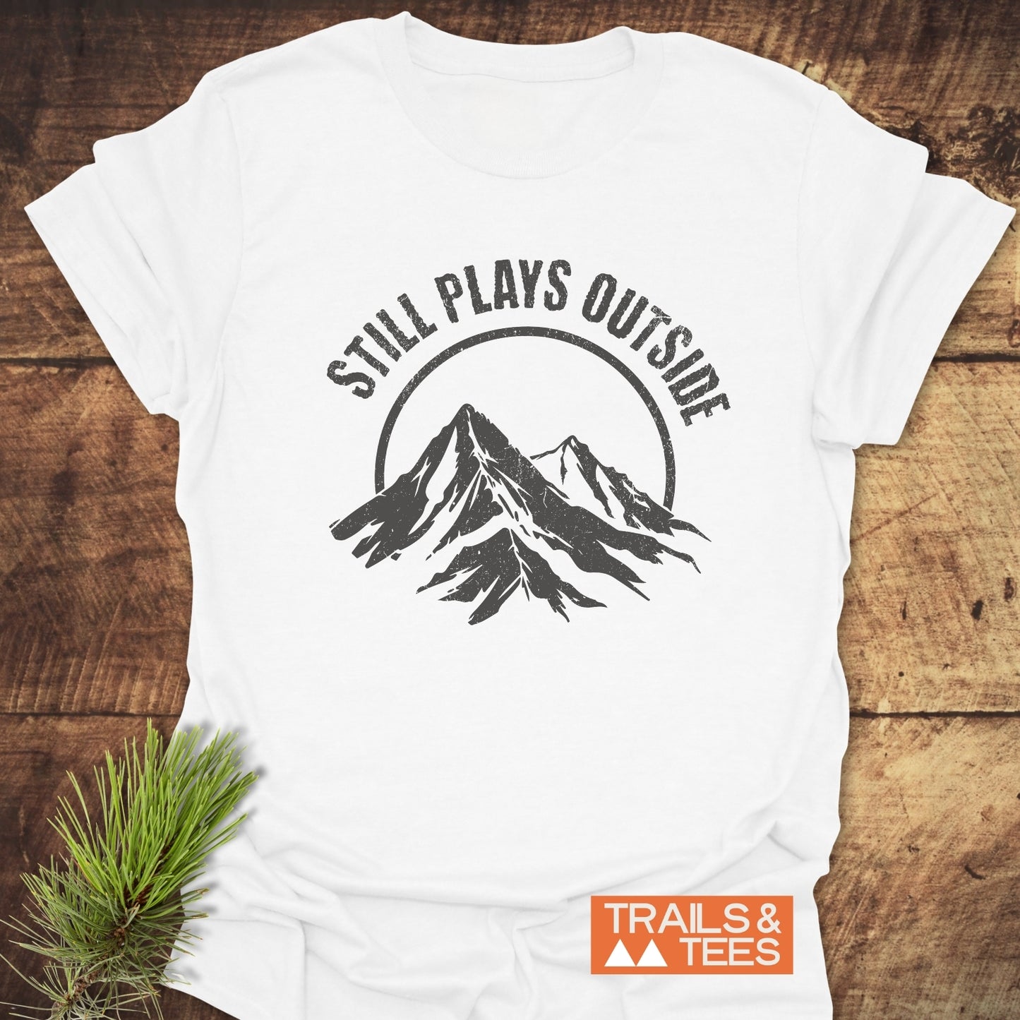 Close-up of Still Plays Outside T-Shirt featuring a mountain logo, crafted from lightweight ring-spun cotton, designed for outdoor enthusiasts.