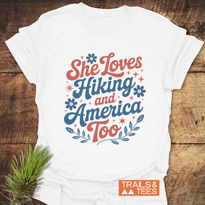 She Loves Hiking And America Too T-Shirt features durable red and blue text on a white tee, ideal for outdoor enthusiasts, crafted from soft, lightweight cotton.