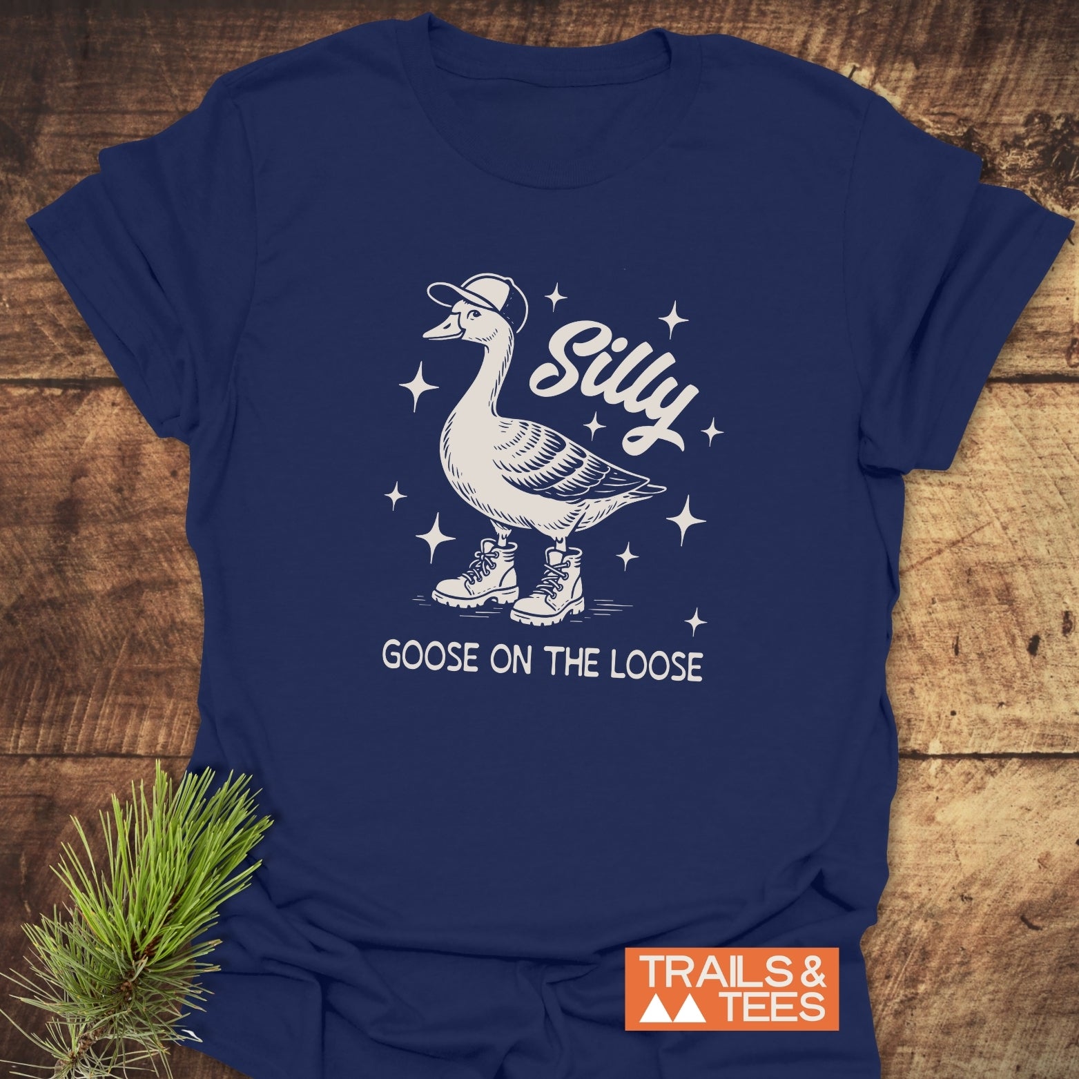 Silly Goose T-Shirt featuring a cartoon goose in a cap and boots, surrounded by starbursts, with TRAILS & TEES branding visible.
