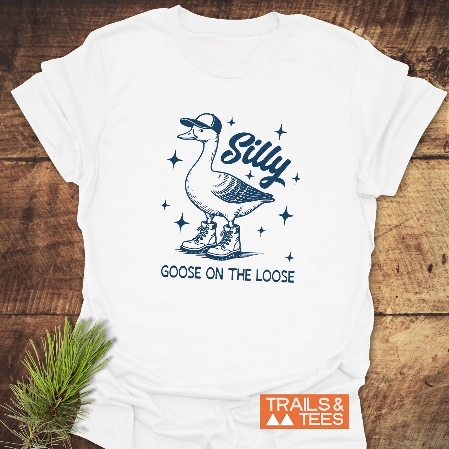 Silly Goose T-Shirt featuring a line drawing of a goose in boots and a cap, with Silly Goose on the Loose text, and TRAILS & TEES logo.