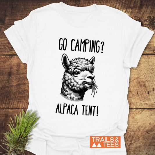 Go Camping? Alpaca Shirt! T-Shirt featuring a sketch of an alpaca's head with a camping pun, laid on wood with “TRAILS & TEES.” logo.