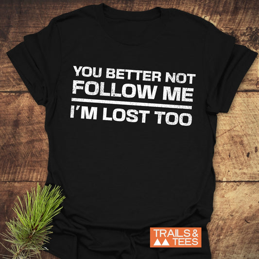 Black You Better Not Follow Me T-shirt with distressed white text, featuring TRAILS & TEES logo and pine sprig for an outdoorsy feel.