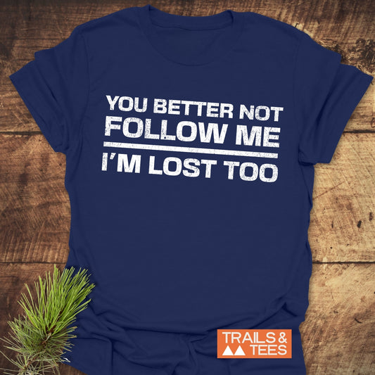 You Better Not Follow Me T-Shirt with white distressed text, laid flat. Includes TRAILS & TEES label and pine sprig for outdoor vibe.