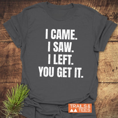 Charcoal-gray I Came. I Saw. I Left. T-shirt on wood, featuring distressed white text. Soft, ring-spun cotton, pre-shrunk, with durable print. Trails & Tees logo visible.