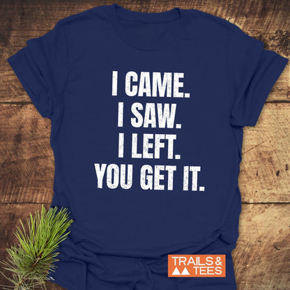 Navy-blue I Came. I Saw. I Left. T-shirt on wood, features white distressed text, orange TRAILS & TEES logo, highlighting comfort and adventure-ready design.
