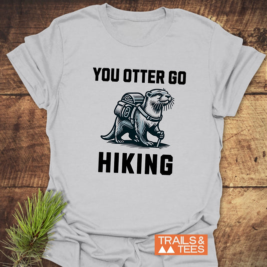 You Otter Go Hiking T-Shirt featuring an otter with backpack illustration, slogan, and Trails & Tees logo, crafted from lightweight cotton for outdoor enthusiasts.