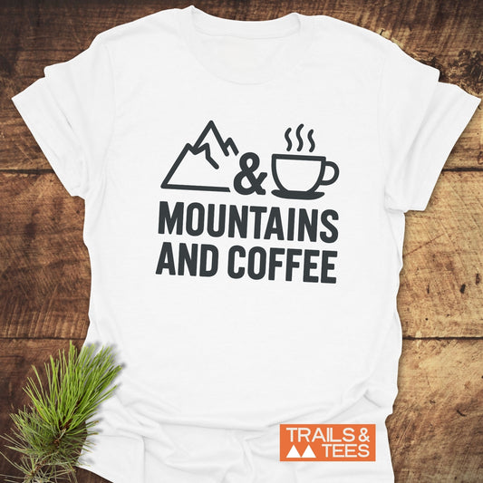 Mountains And Coffee T-Shirt featuring a line-art mountain and coffee cup design, with a Trails & Tees logo, on soft, durable ring-spun cotton.