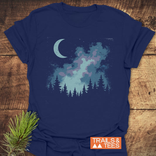 Moonlit Forest T-Shirt showcases a serene nighttime design with a crescent moon and nebula above pine silhouettes, embodying outdoor adventure spirit in soft, durable cotton.