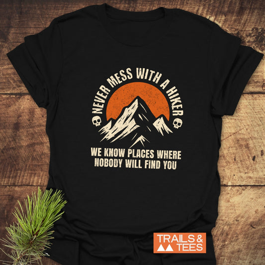 Never Mess With A Hiker T-Shirt featuring a mountain silhouette and bold slogans, crafted from soft cotton for comfort, displaying the Trails & Tees logo.