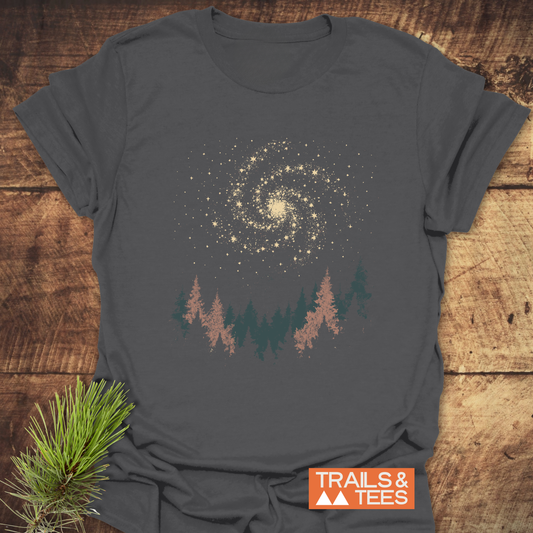 Woodland Nightsky T-Shirt featuring a galaxy and pine tree graphic, designed for outdoor enthusiasts. Made from soft cotton, showcasing durability and eco-friendly production.