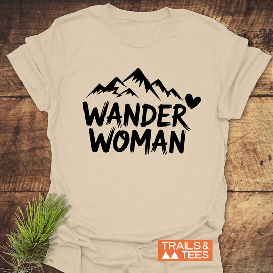 Wander Woman T-Shirt featuring bold mountain graphic and text, crafted from soft cotton for comfort, with durable prints, laid flat with pine sprig accent.