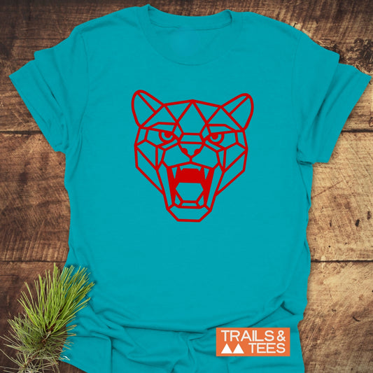 Geometric Cougar T-Shirt featuring a red low-poly big-cat head on turquoise-blue fabric, laid flat. Includes TRAILS & TEES logo and pine needles for a natural touch.