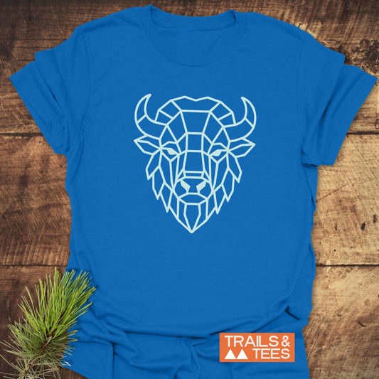 Geometric Bison T-Shirt featuring a low-poly bison head illustration on bright-blue cotton, styled with pine sprig, showcasing Trails & Tees logo.