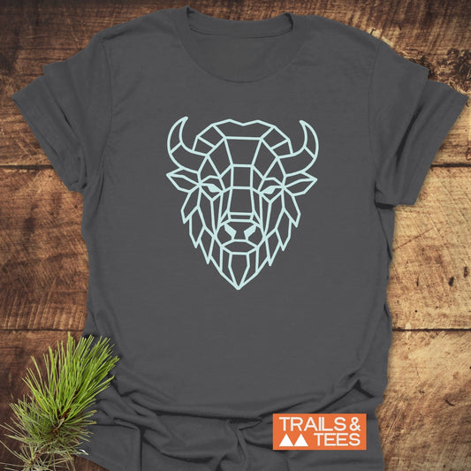 Geometric Bison T-Shirt on rustic wood, featuring a light-blue bison head outline. Includes TRAILS & TEES logo and pine sprig accent.