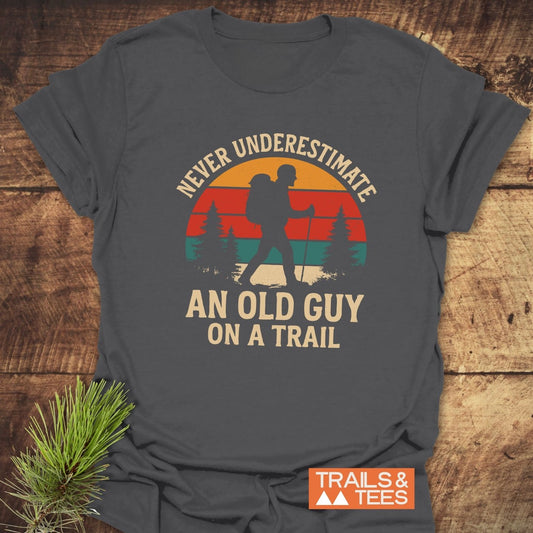 Never Underestimate T-Shirt featuring a vintage hiker graphic and slogan, crafted from soft ring-spun cotton with durable prints, ideal for outdoor enthusiasts.