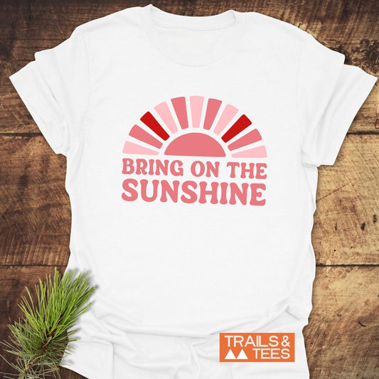 Bring On The Sunshine T-Shirt with half-sun graphic and retro font slogan, laid out with pine sprig; features soft, ring-spun cotton for outdoor adventures.