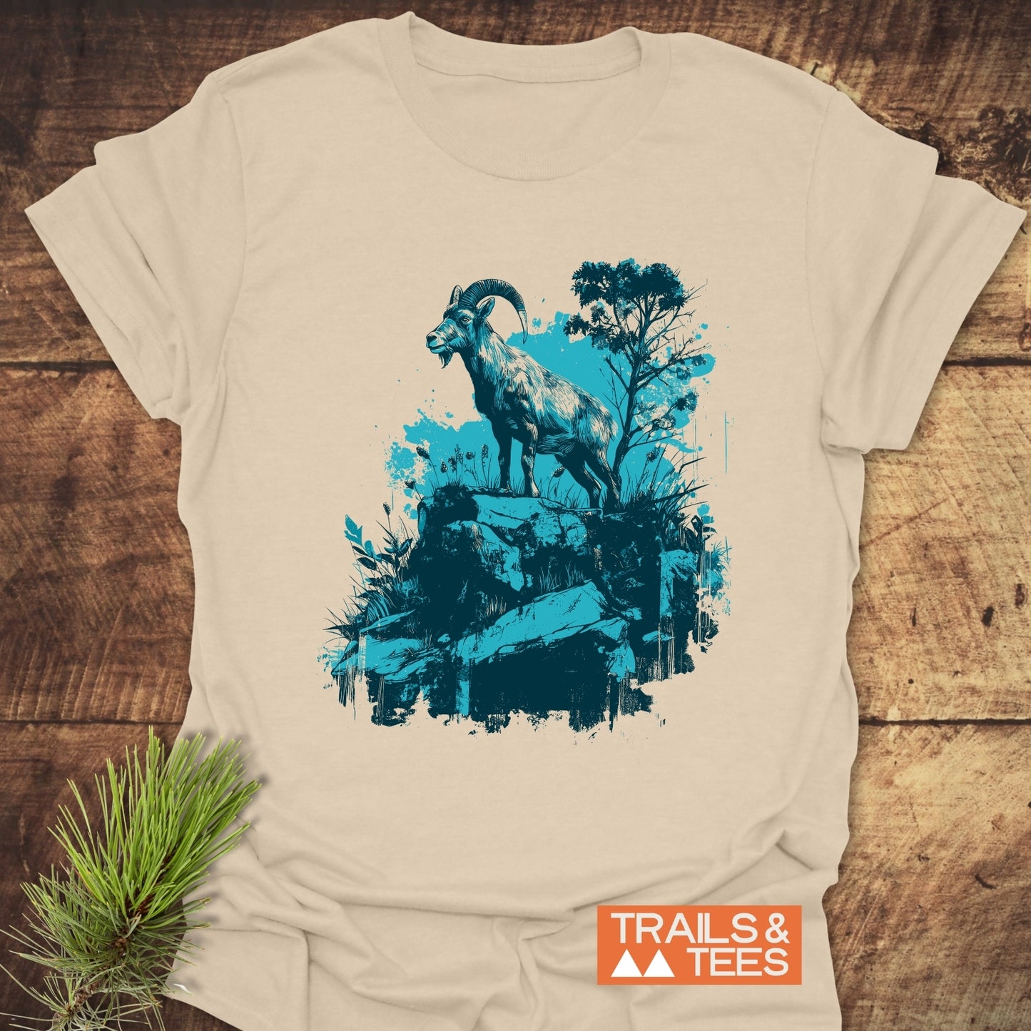 Wild and Steady – Mountain Goat T-Shirt displaying a teal and dark blue mountain goat graphic, highlighting its soft cotton fabric and durable print.