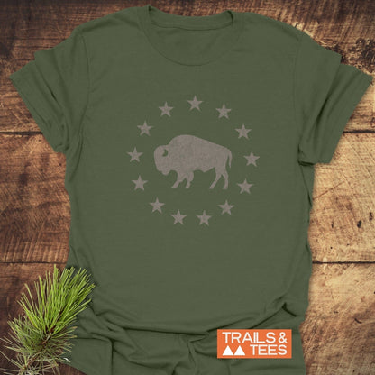 Born to Roam – Vintage Bison T-Shirt featuring a distressed bison graphic with stars, laid on wood. Includes TRAILS & TEES logo and pine sprig accent.