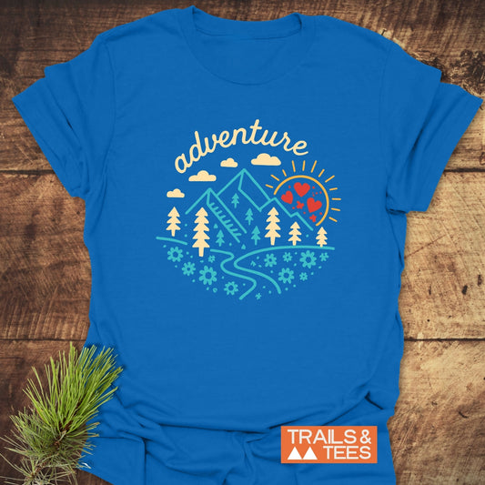 Adventure Whimsical T-Shirt with nature-themed graphic: mountains, trees, sun, and path. Crafted from soft cotton, durable prints, pre-shrunk, taped shoulders, no side seams.