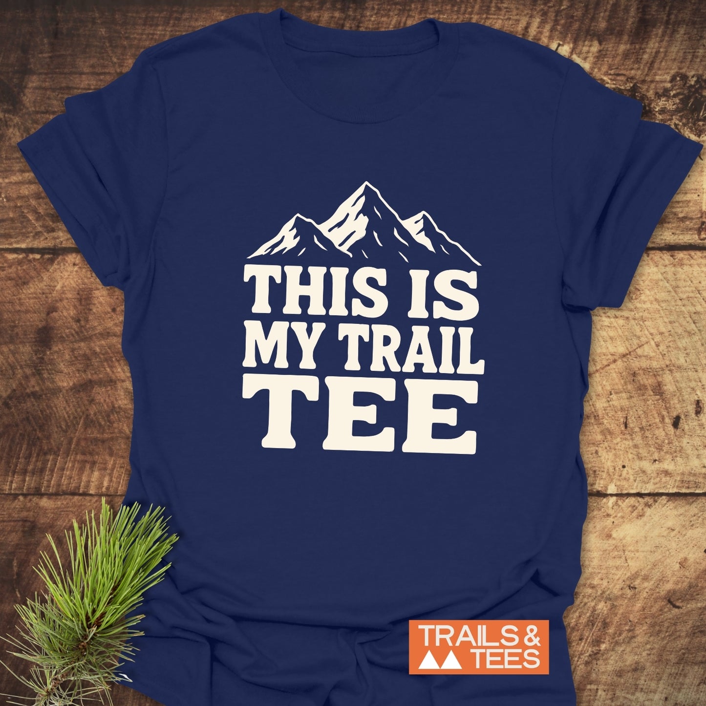 Navy-blue T-shirt with a white mountain-peak graphic and “THIS IS MY TRAIL TEE” text, featuring outdoor-themed design by Trails & Tees.