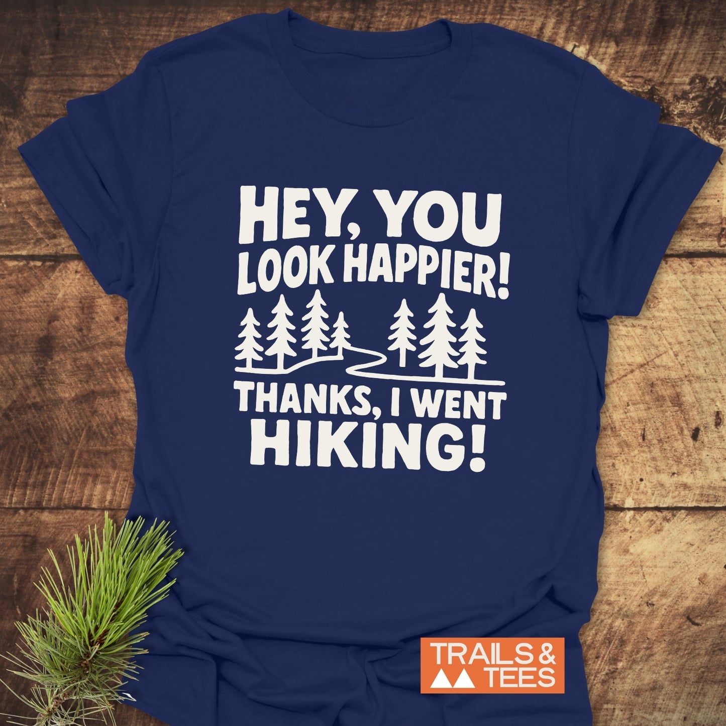 Hey, You Look Happier T-Shirt with evergreen trees and hiking text on navy-blue, crafted from soft cotton, featuring durable prints and eco-friendly production.