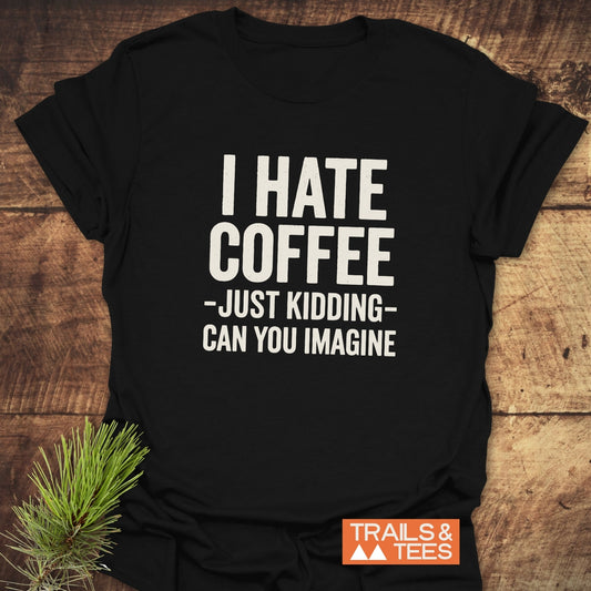 I Hate Coffee T-Shirt on wooden surface, featuring white text and Trails & Tees logo. Made from soft cotton, perfect for outdoor adventures.
