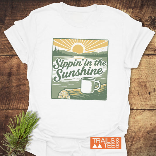 Sippin' In The Sunshine T-Shirt with vintage lake sunrise graphic on soft, ring-spun cotton. Features durable print and Trails & Tees logo.