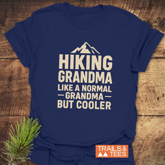 Navy-blue Hiking Grandma T-Shirt with mountain graphic and text, styled with pine sprig. Crafted from soft cotton, durable print, pre-shrunk for comfort.