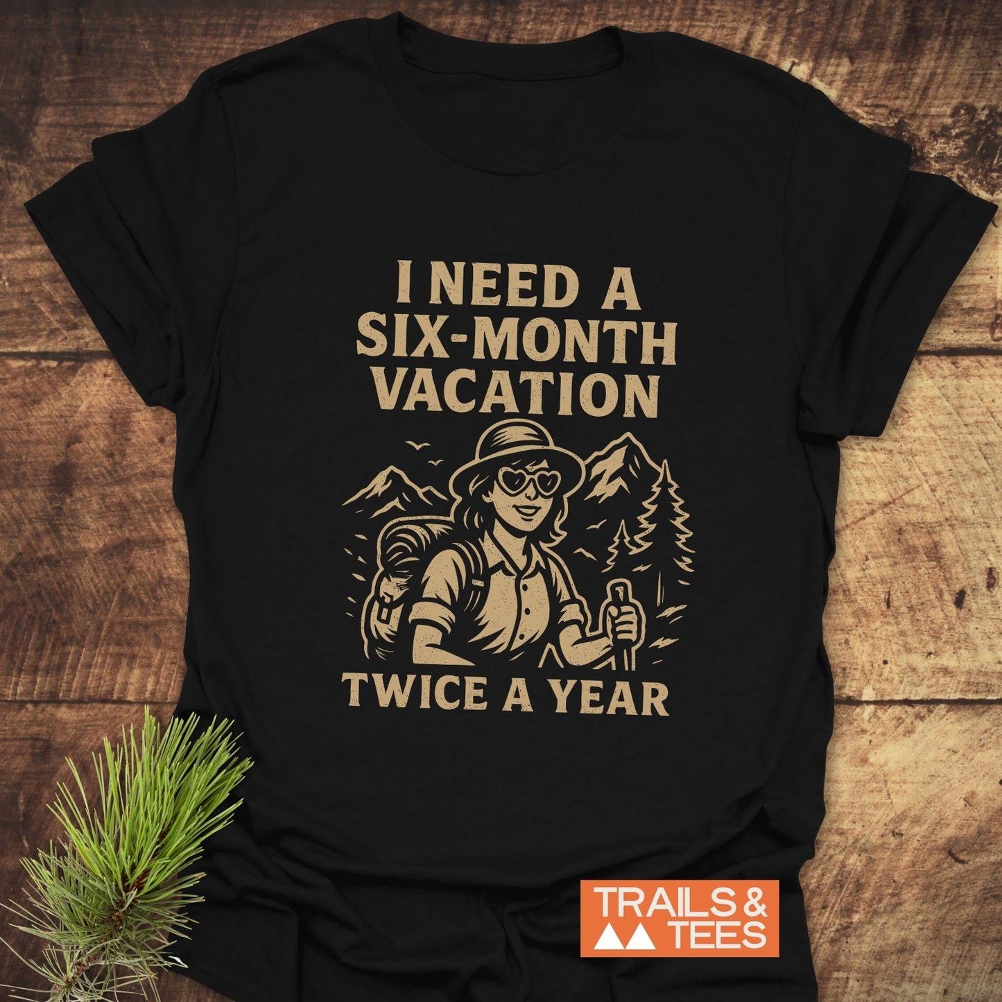 Six-Month Vacation T-Shirt featuring a cartoon hiker with mountains and trees, vintage-style slogan, and Trails & Tees logo on soft, comfortable cotton.
