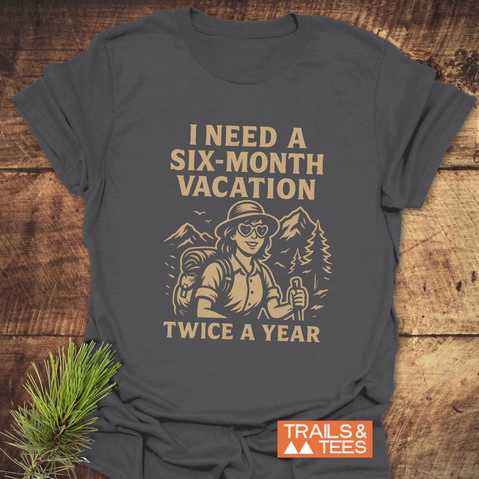Charcoal-grey Six-Month Vacation T-Shirt featuring a tan vintage hiker illustration with slogan, offering trail-tested comfort and durable design.