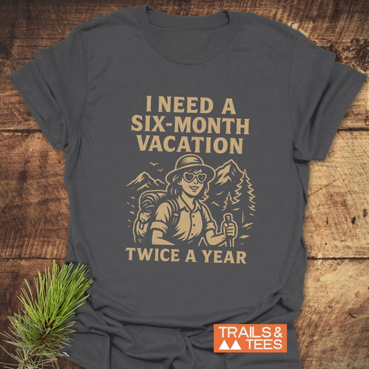 Charcoal-grey Six-Month Vacation T-Shirt featuring a tan vintage hiker illustration with slogan, offering trail-tested comfort and durable design.