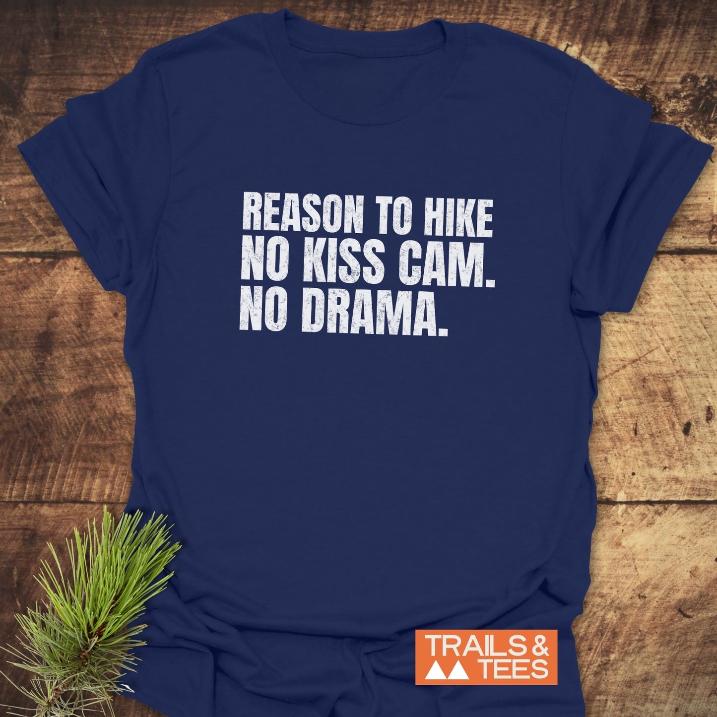 Reason To Hike: No Kiss Cam T-Shirt, navy-blue with white text, laid on wood. Features durable print, soft cotton, and sustainable design from Trails & Tees.