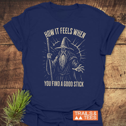 Good Stick T-Shirt featuring a bearded wizard sketch, crafted from soft cotton for comfort, with durable prints and a Trails & Tees logo.