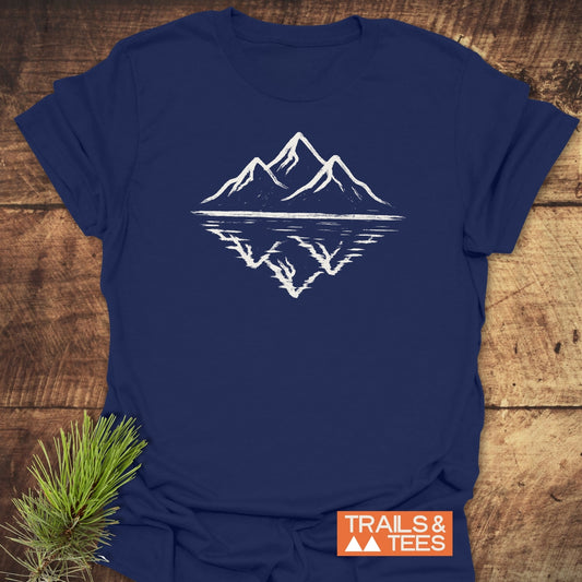 Mountain Reflection T-Shirt featuring a hand-sketched mountain and reflection design. Made from soft, durable cotton, ideal for outdoor enthusiasts. Includes TRAILS & TEES logo.
