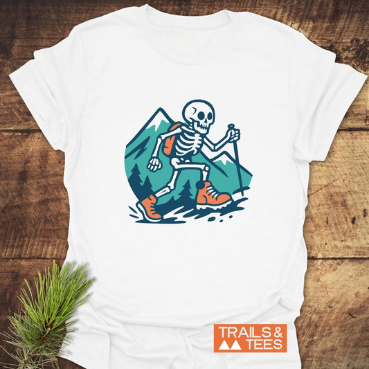 Long Way To The Top – Skeleton Hiking T-Shirt: White tee featuring cartoon skeleton hiker with mountain backdrop, emphasizing outdoor adventure and comfort.