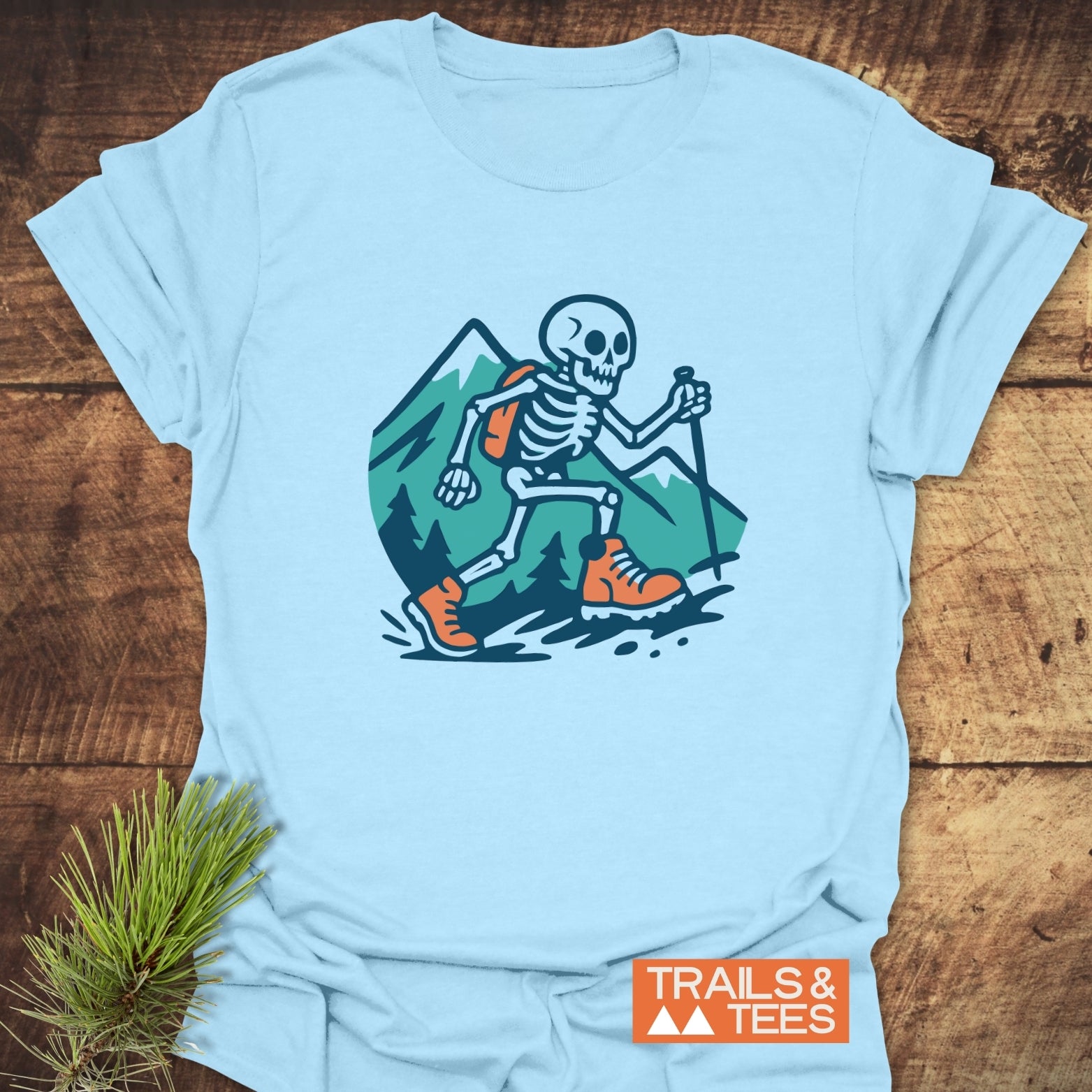 Long Way To The Top – Skeleton Hiking T-Shirt featuring a cartoon skeleton in hiking gear against mountain backdrop, symbolizing outdoor adventure and comfort.
