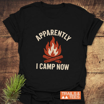 Apparently Camping T-Shirt with a campfire graphic and text, laid on wood. Soft, ring-spun cotton, pre-shrunk, durable print.