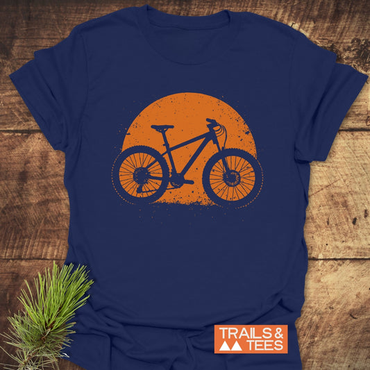 Grunge Mountain Bike T-Shirt with a distressed bike graphic on navy, laid on wood. Features soft cotton, durable print, and outdoor-inspired style.