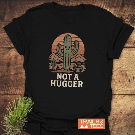 Not A Hugger T-Shirt featuring a grumpy cactus in a desert scene, crafted from soft cotton for comfort, with durable prints and pre-shrunk for a reliable fit.