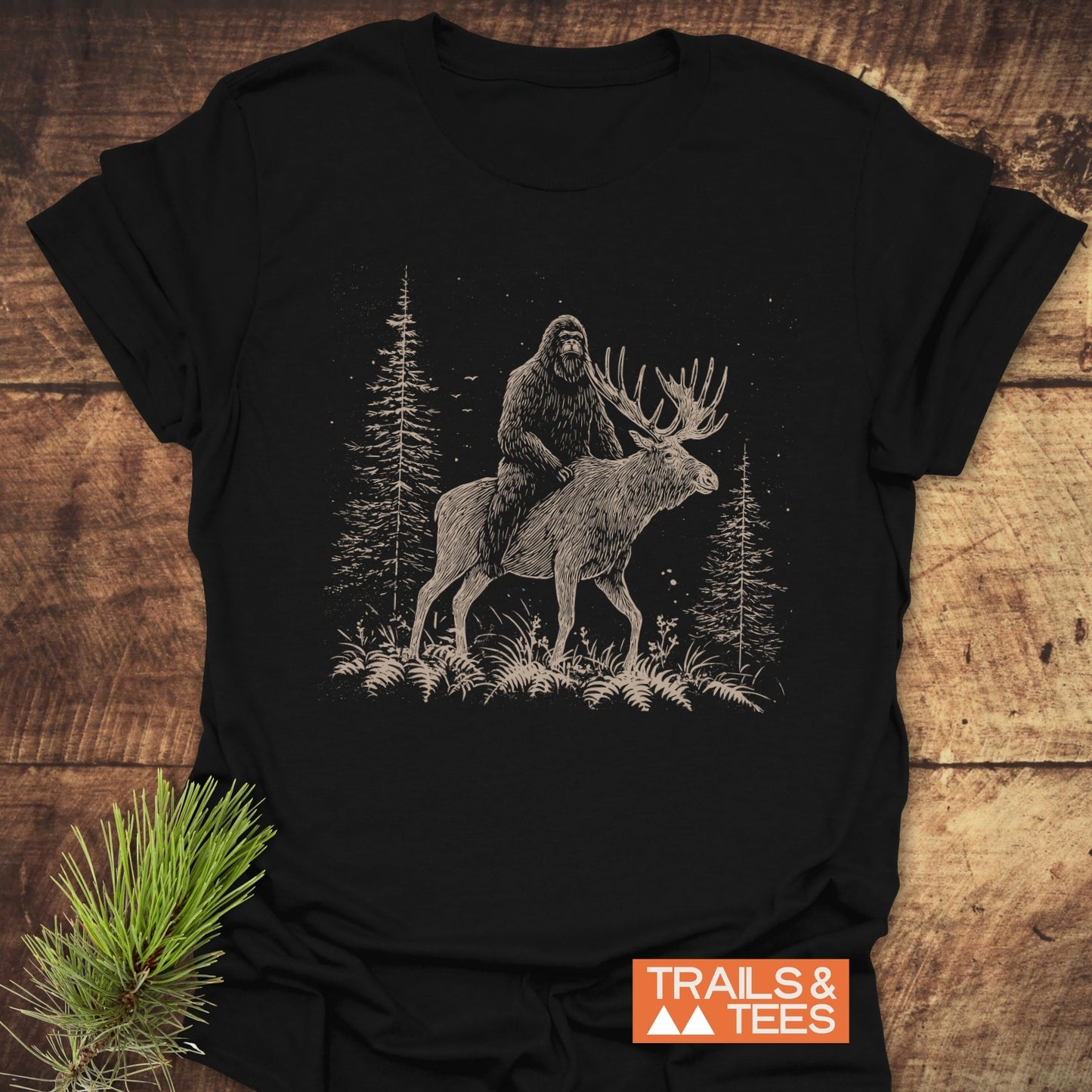 Best Friends Bigfoot T-Shirt featuring Bigfoot on a moose in a forest scene, designed for comfort and durability with trail-tested, lightweight cotton.