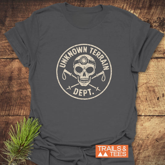 Unknown Terrain Dept. T-Shirt with distressed logo featuring a skull and hiking poles. Crafted from soft cotton, ideal for outdoor adventures. Brand: TRAILS & TEES.