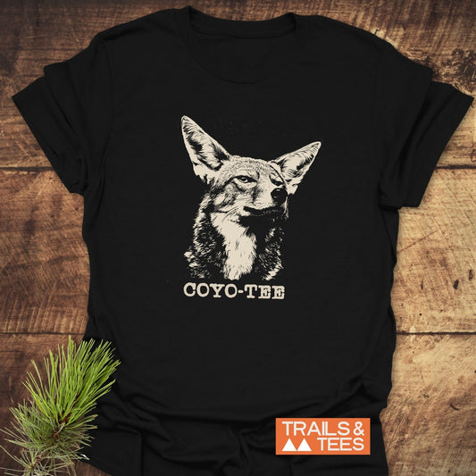 Coyo-Tee T-Shirt featuring a coyote illustration and COYO-TEE caption, crafted from soft cotton for comfort and durability, laid on a wooden surface.
