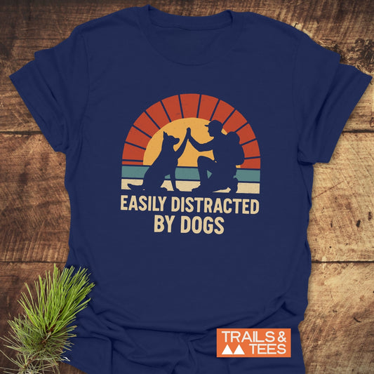 Navy-blue Easily Distracted By Dogs T-shirt featuring a retro graphic of a person high-fiving a dog against a stylized sunrise, ideal for outdoor enthusiasts.