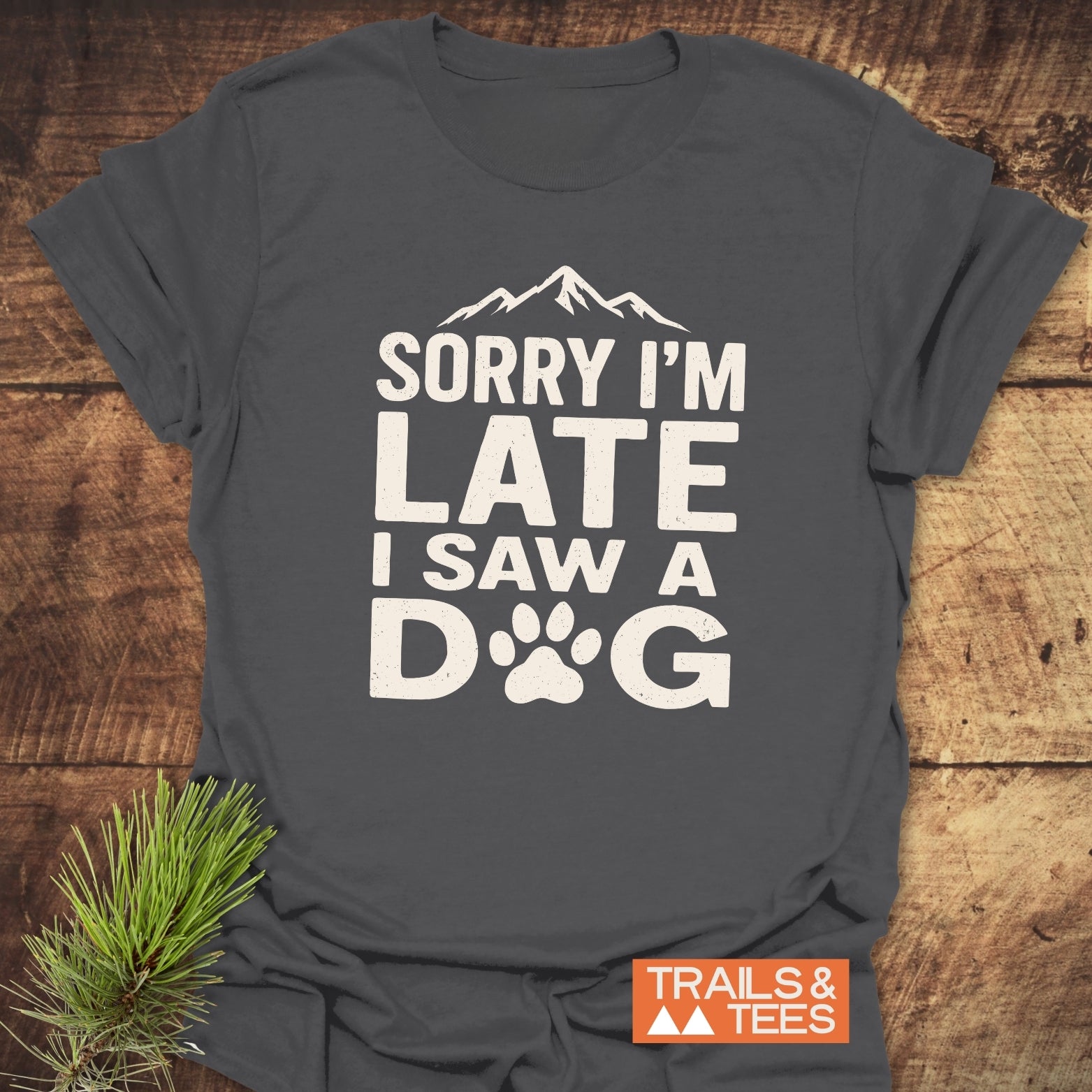 I Saw A Dog T-Shirt with mountain silhouette, off-white text, and paw print. Trail-tested comfort, soft cotton, pre-shrunk. 'TRAILS & TEES' logo included.