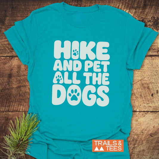Teal crew-neck t-shirt with HIKE AND PET ALL THE DOGS slogan in white, featuring paw prints; Trails & Tees logo visible.