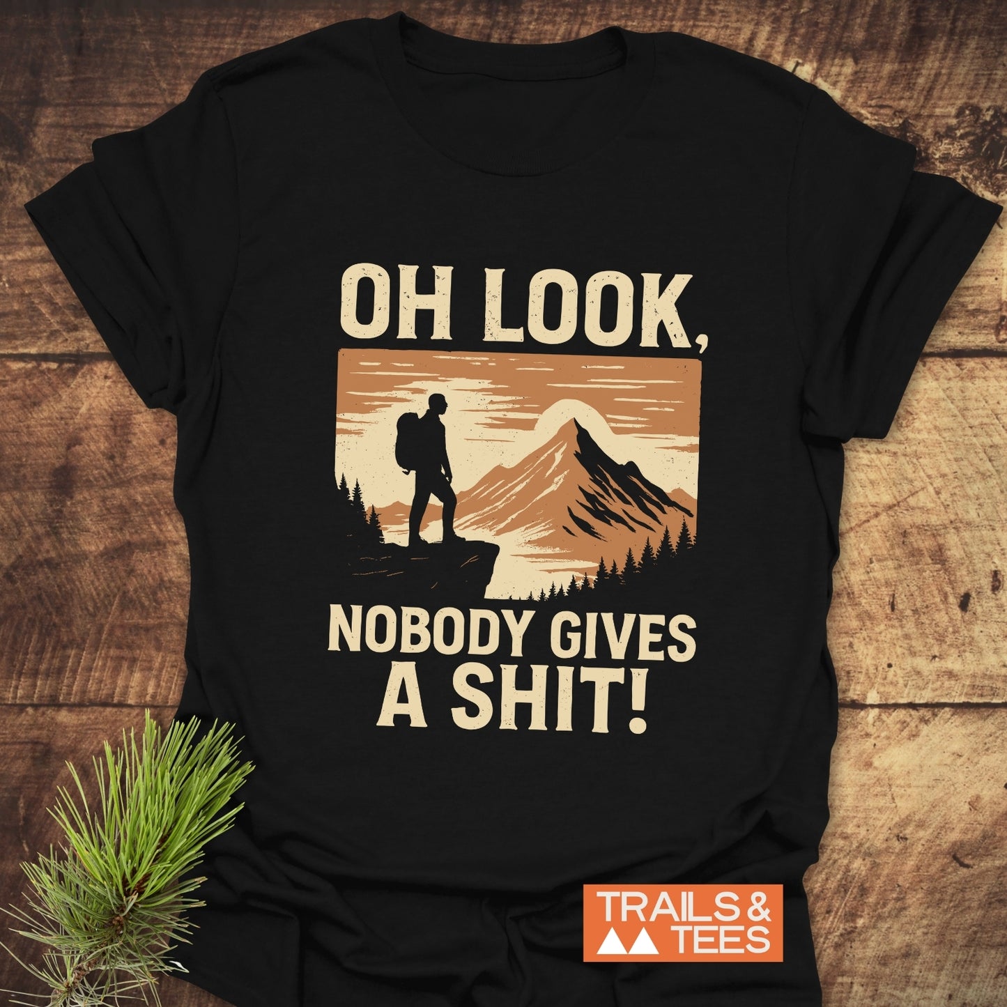 Oh Look! Retro T-Shirt featuring a hiker graphic with humorous text, crafted from soft cotton for comfort, displayed with a pine sprig.