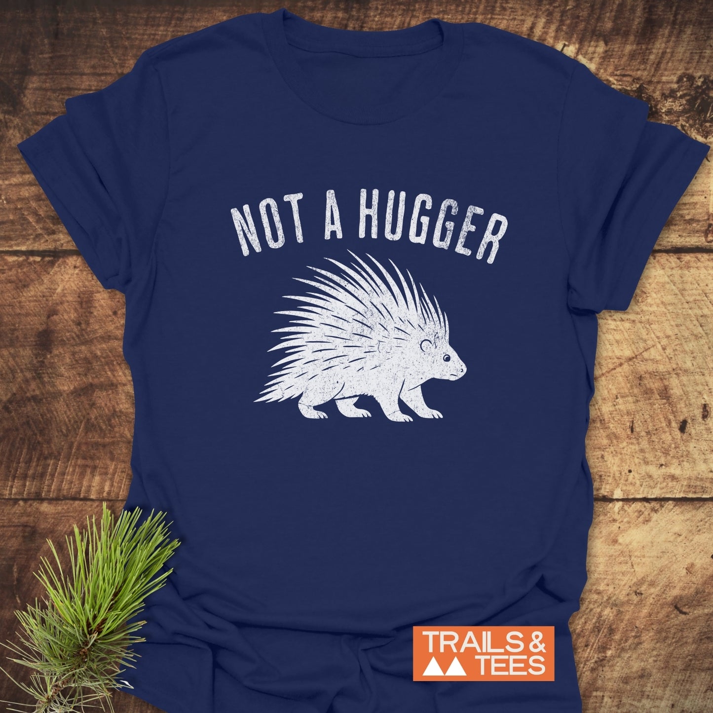 Not A Hugger T-Shirt with porcupine print on soft navy-blue cotton, laid on wood. Designed for comfort and outdoor adventures.
